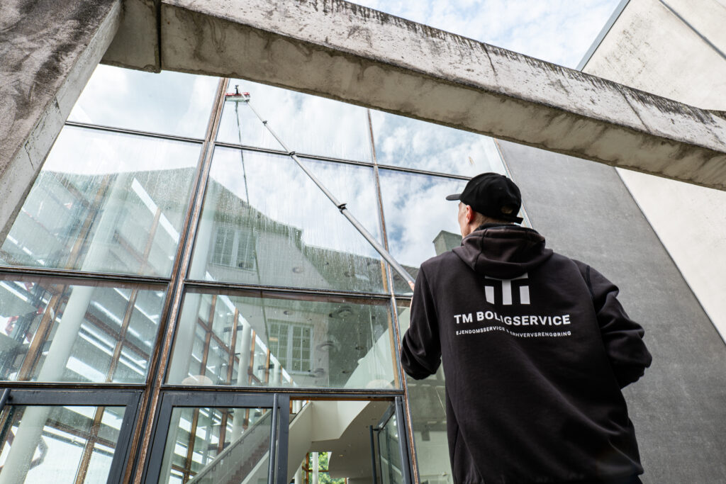 Vinduespudser fra TM Boligservice ved glasfacaden på en erhvervsejendom